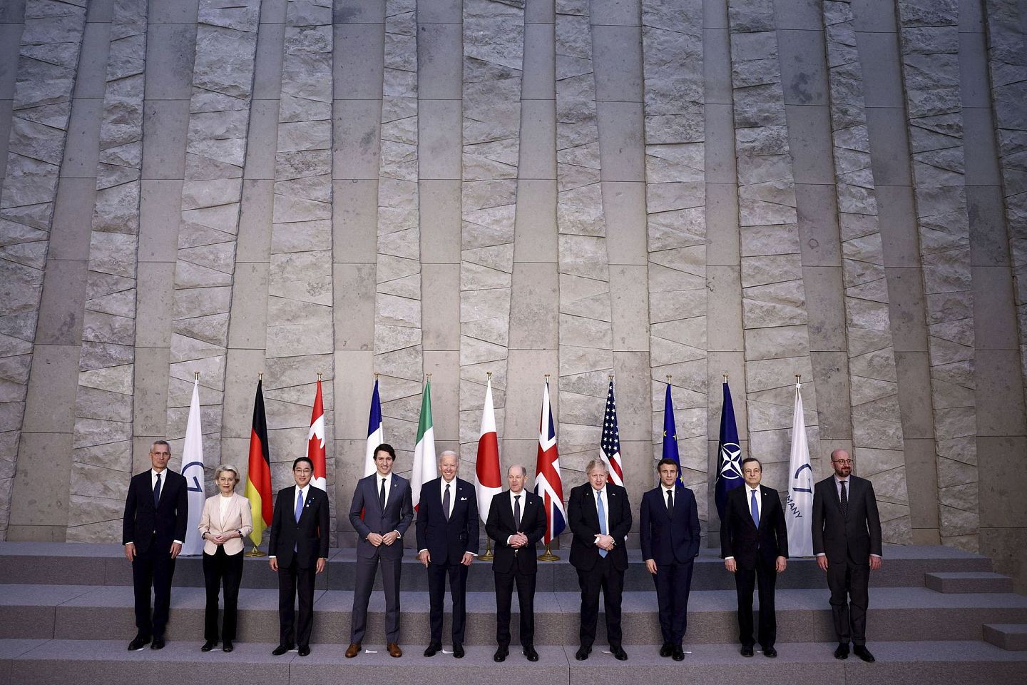 2022 年 3 月 24 日，在比利时布鲁塞尔举行的北约峰会上，意大利总理德拉吉和欧洲理事会主席米歇尔为 G7 领导人合影留念，讨论俄罗斯入侵乌克兰议题。左起北约秘书长斯托尔滕贝格、欧盟委员会主席冯德莱恩、日本首相岸田文雄、加拿大总理特鲁多、美国总统拜登、德国总理肖尔茨、英国首相强生、法国总统马克龙。（AP）