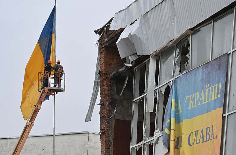 图为基辅州内马卡里夫市工人10日在毁损建物后方更换全新乌克兰国旗。 （法新社）
