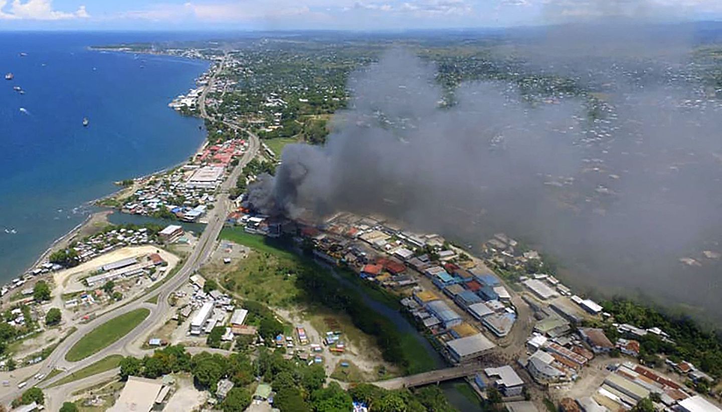 2021年11月25日，这是所罗门群岛首都霍尼亚拉骚乱的第二天，多个建筑物被焚烧冒出浓烟。（Getty）