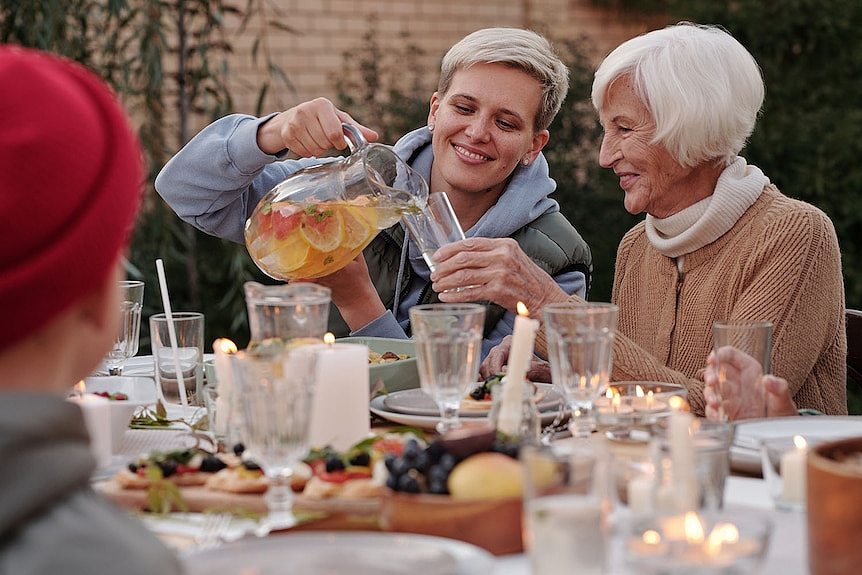 A younger woman with an elderly woman having a party at a happy family gathering in a backyard.