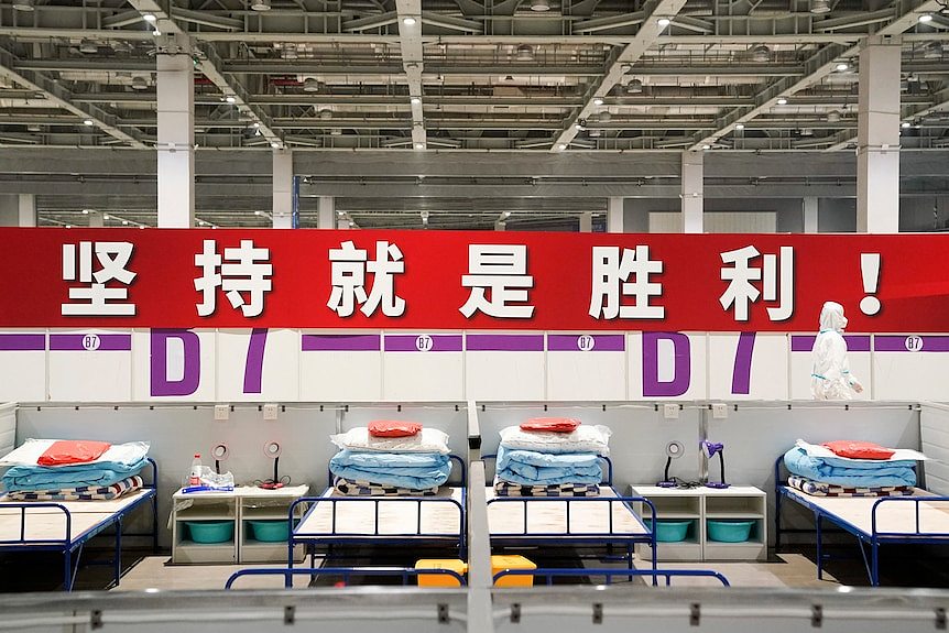 A worker in protective clothing walks past a banner reading 