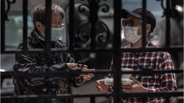 上海的一个被封锁的住宅区，两位老人在大门口交谈