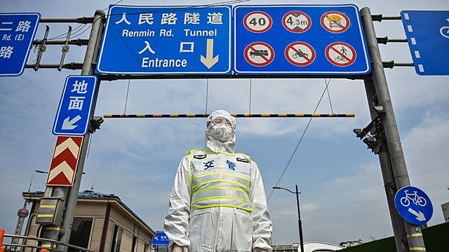 3月28日，一名身穿防护服的上海交管控制进入浦东区方向的隧道入口