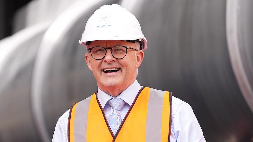 Anthony Albanese laughs while wearing a hard hat and orange high-vis vest.