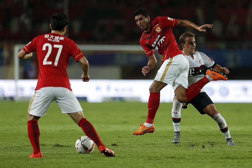 Three footballers, one is Asian, one is Latin American, one is Caucasian. 