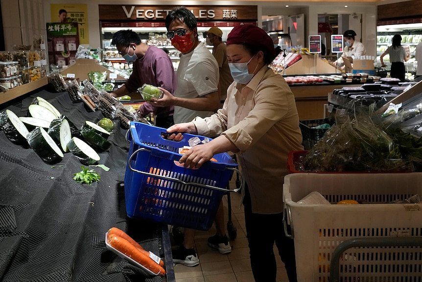 Shoppers look through bare vegetable shelves at a Beijing supermarket.