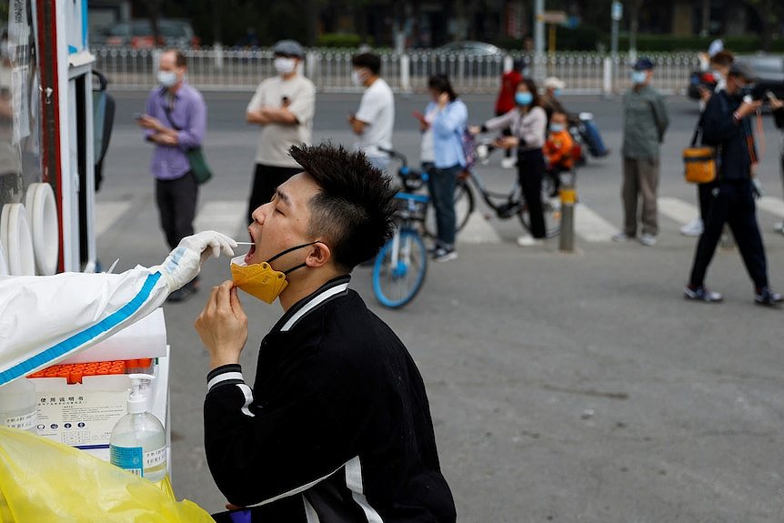 A man has his throat swabbed at an outdoor testing site. 