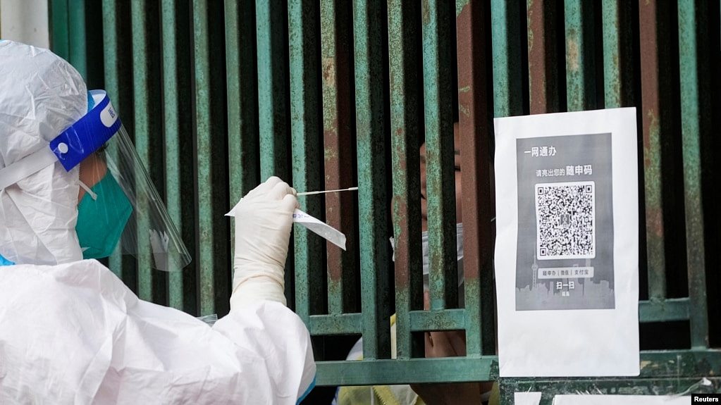 上海一名医务人员从一个固定新冠核酸采样点里给市民进行检测。（2022年5月5日）