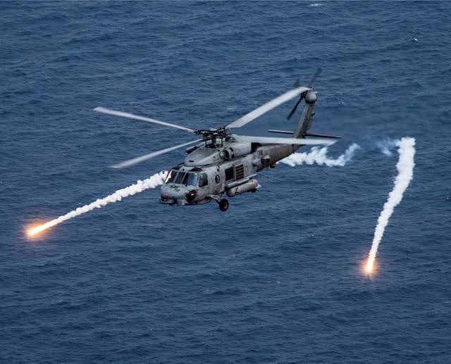 美国海军MH-60R海鹰直升机在菲律宾海与附近的“卡尔文森”号航空母舰（CVN 70）一起参加演习时发射箔条弹（2017年4月24日资料照片）