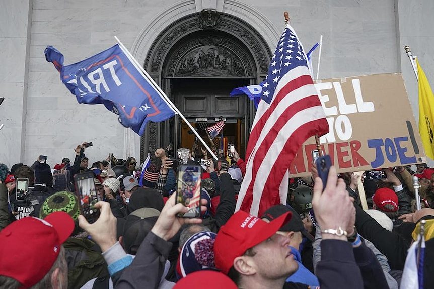 Rioters in the US hold up American flags outside the Capitol building 
