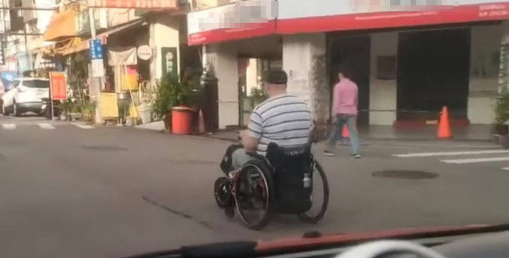 轮椅阿北大摇大摆地行驶在马路中。 （图／翻摄自爆废公社2馆）