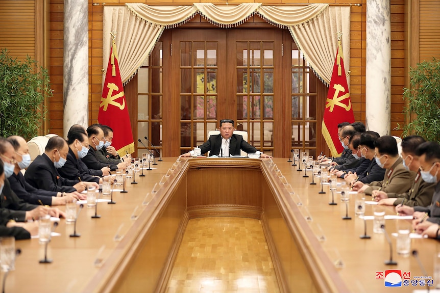 Kim Jong Un at a meeting with officials and not wearing a mask. 