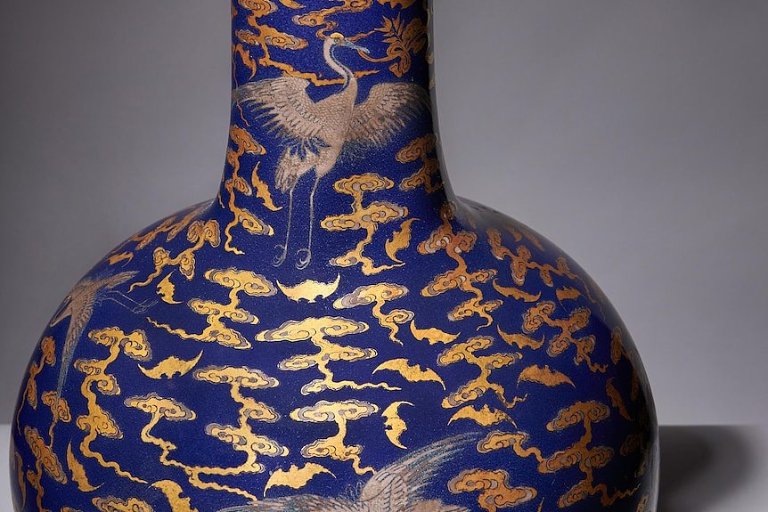 A Qianlong-era blue vase with cranes and bats in silver and gold on it.