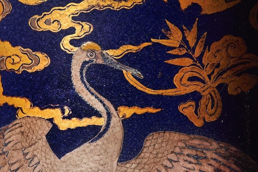 A silver crane and golden bats on a blue background