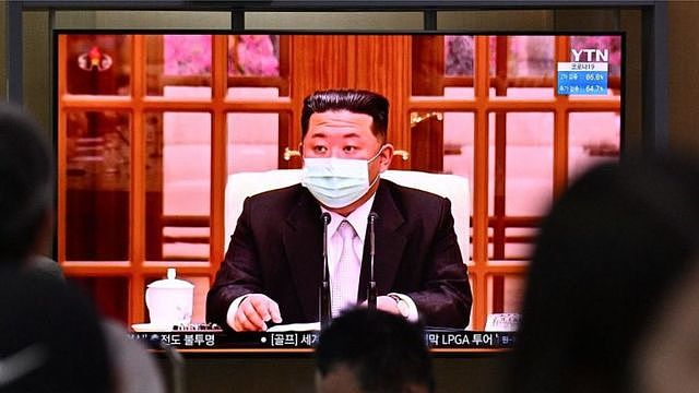 People sit near a screen showing a news broadcast at a train station in Seoul on May 12, 2022, of North Koreas leader Kim Jong Un appearing in a face mask on television for the first time to order nationwide lockdowns after the North confirmed its first-ever Covid-19 cases.