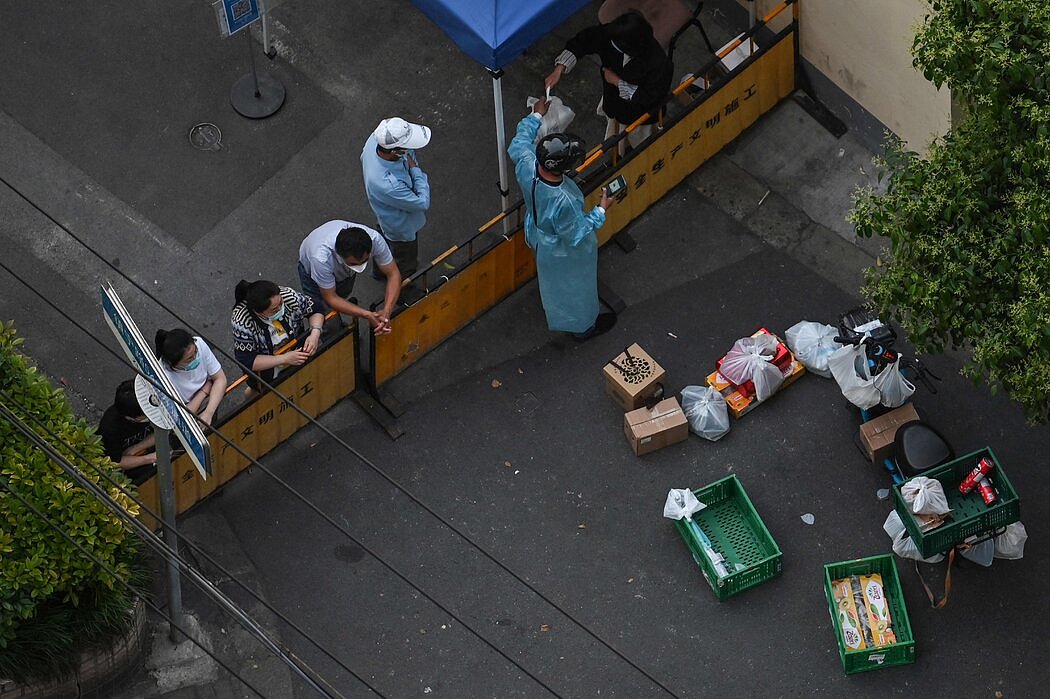一位居民从外卖小哥手中接过食物，上周二摄于上海。食品短缺和封城措施的混乱在网上激起了愤怒，审查人员一直在努力控制网络舆论。