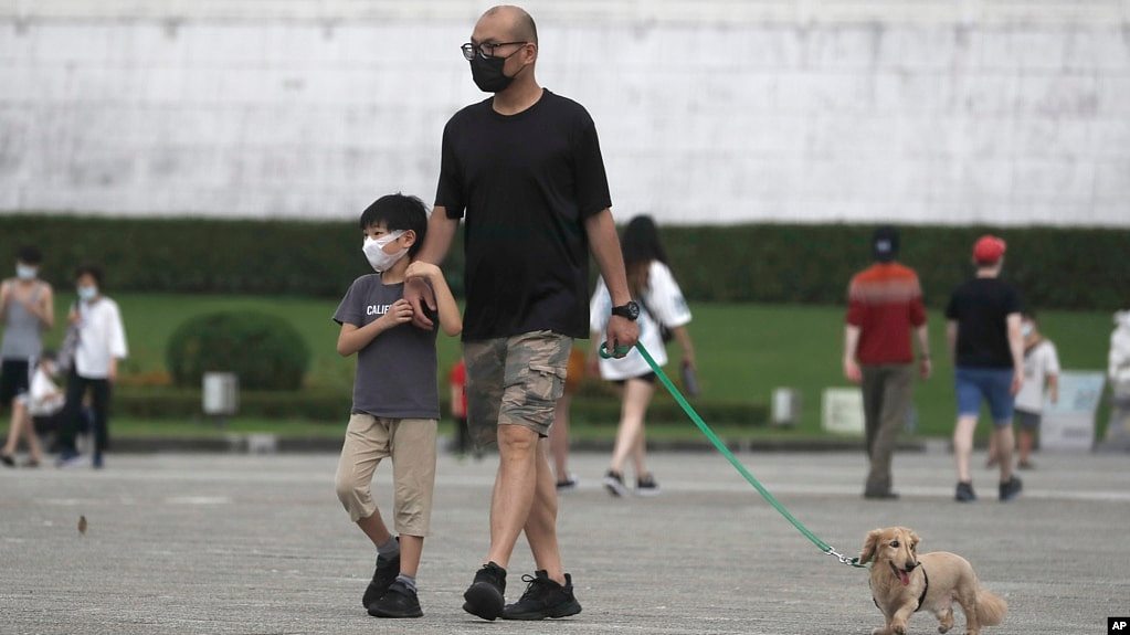 台北市民戴着口罩遛狗散步。（2022年4月27日）