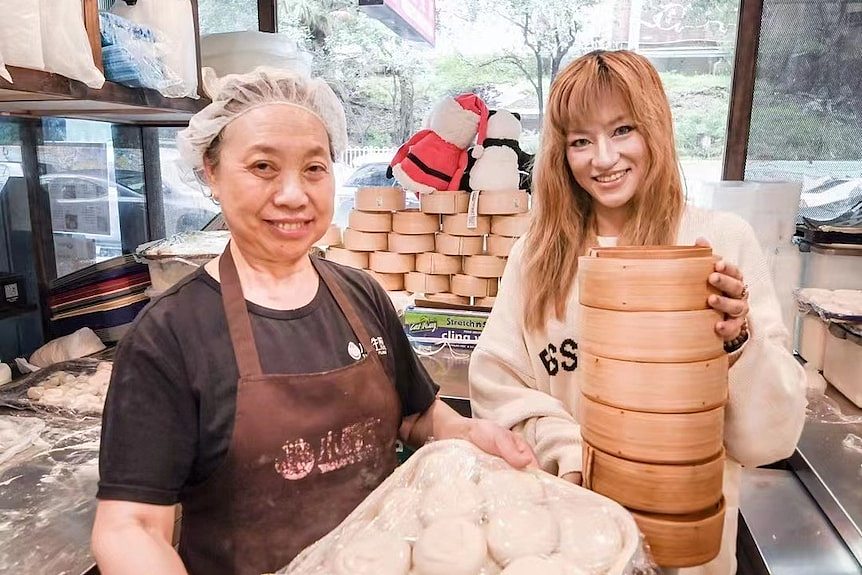 Two ladies are holding steamed dumplings 