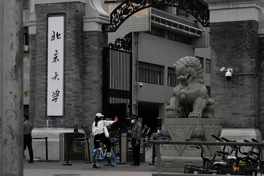 今年5月，一名女子在获许进入北京大学校园前向保安展示证件。