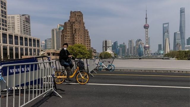 一名男子在上海骑着自行车穿过桥上的疫情封锁路障