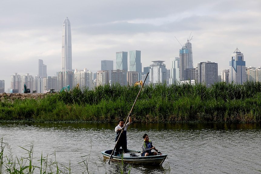 A man in a boat with high-rise buildings in the background.