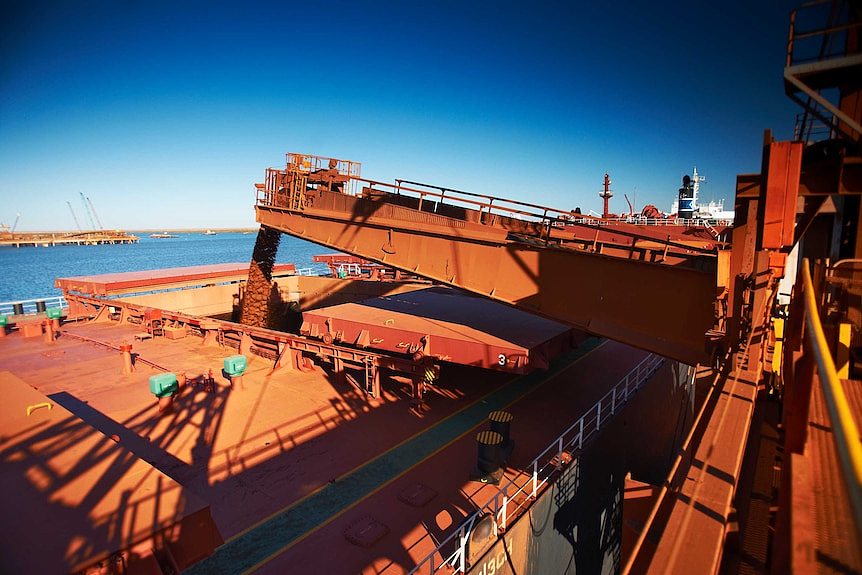 A wide shot of iron ore being loaded onto a ship in Port Hedland.