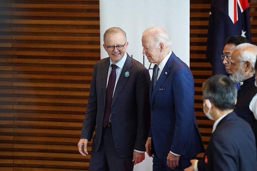 Two men in suits talk to eavch other.