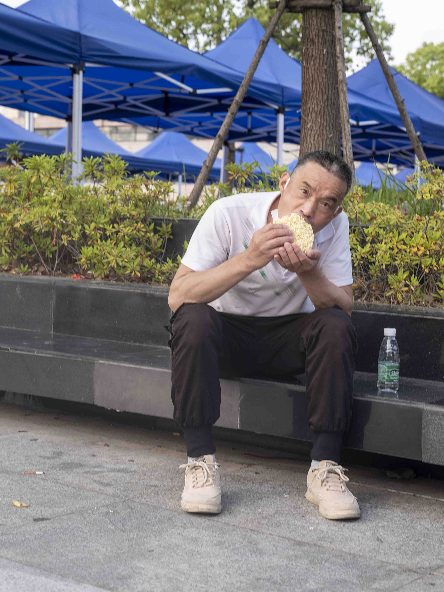 2022年5月26日，虹桥火车站前，一名男子在干吃方便面饼。