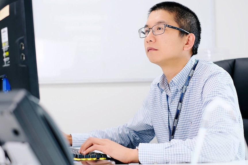 一名穿着条纹衬衫的男子看着电脑屏幕