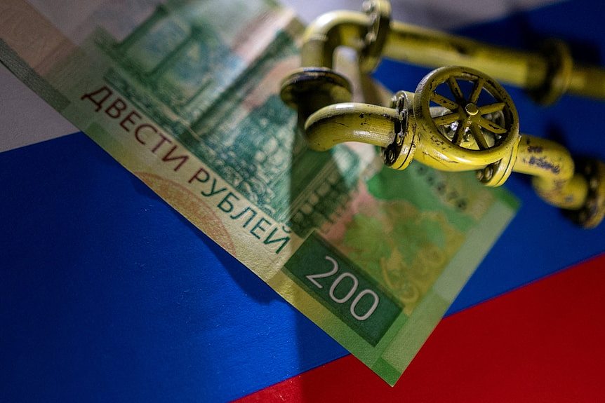 A model of the natural gas pipeline is placed on Russian Rouble banknote and a flag.