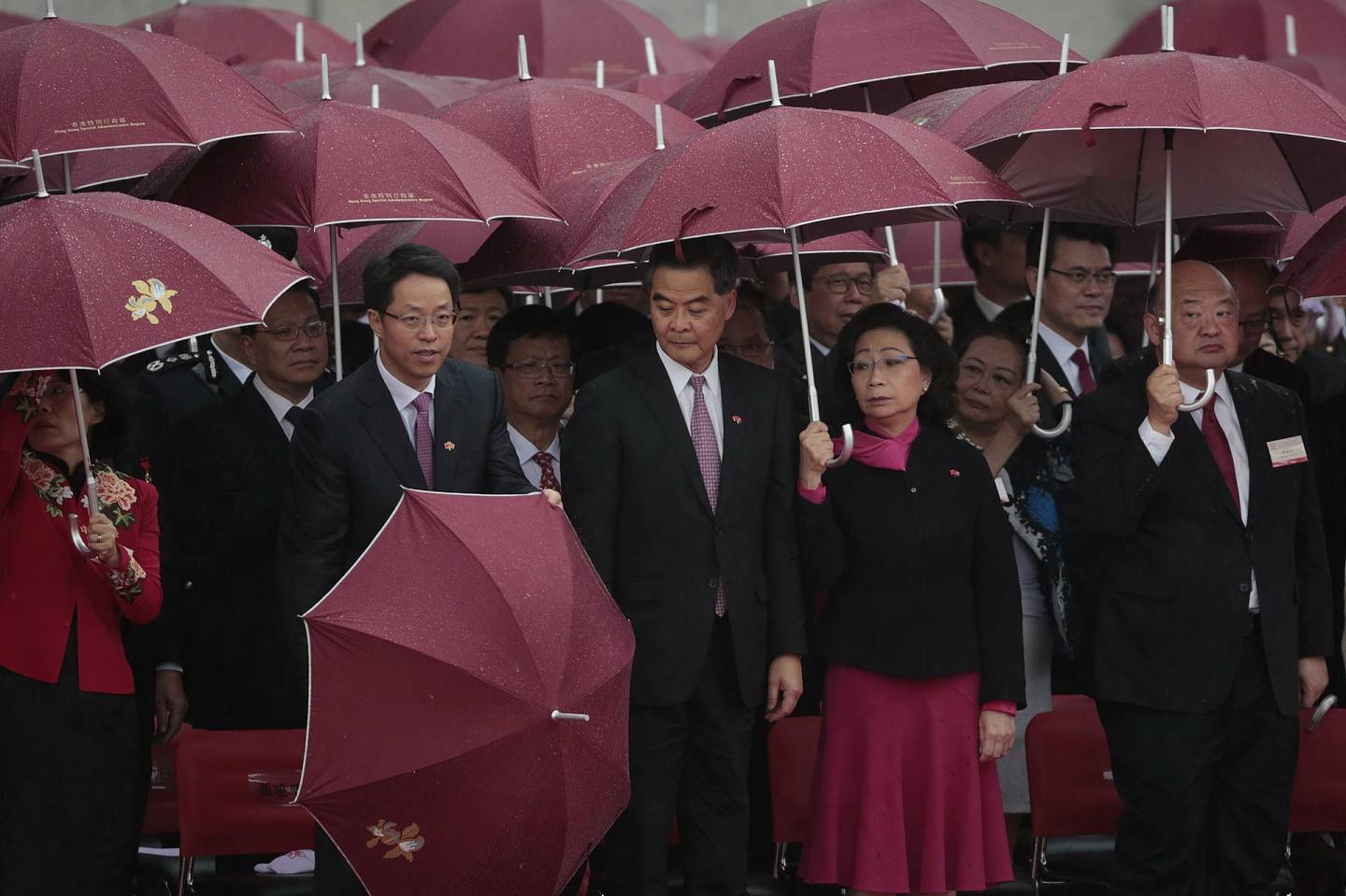 2016年，早上升旗儀式國歌奏起時，中聯辦主任張曉明即收起雨傘，在旁的特首梁振英夫婦其後跟隨。（李澤彤攝）