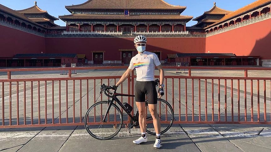 一名穿着自行车服的男子站在北京的一幢古建筑前