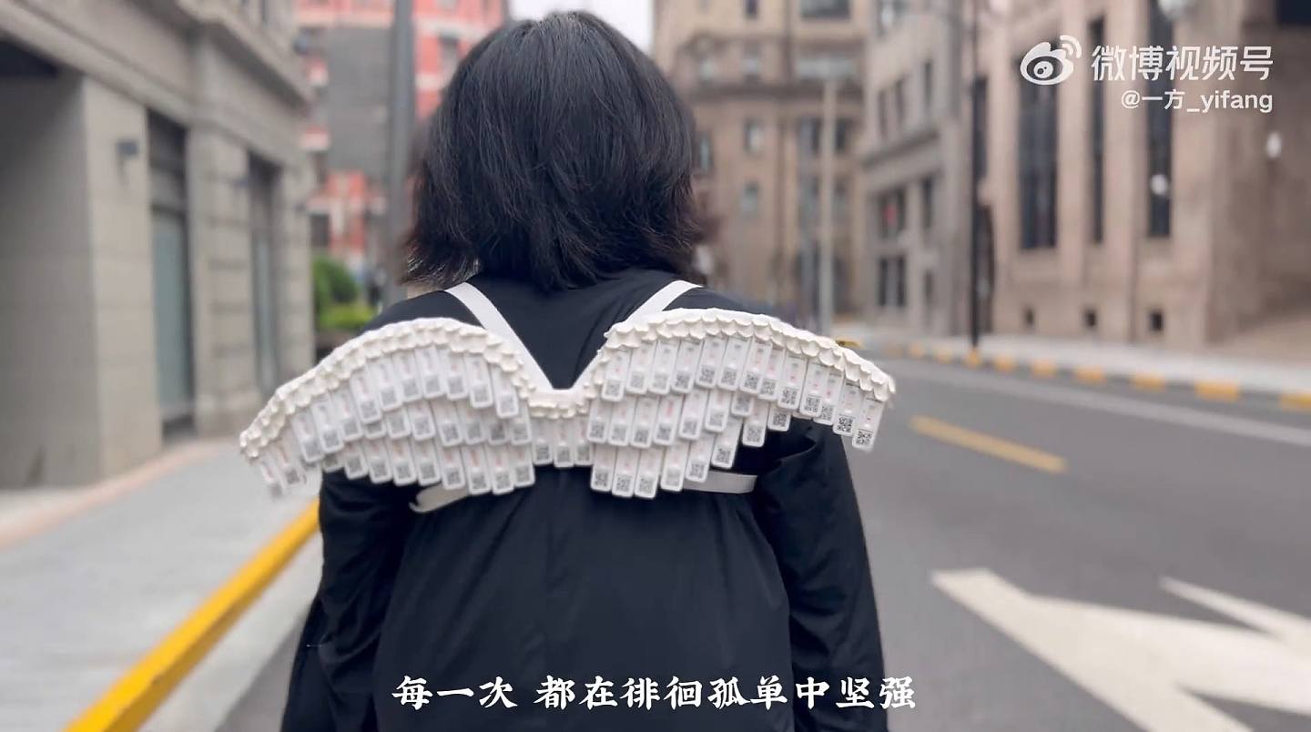 上海有对情侣用61支检测阴性的快速抗原测试棒，制作成1对「阴性的翅膀」，背在背上游走上海著名景点，并拍成影片庆祝解封。 （「一方_yifang」微博影片截图）