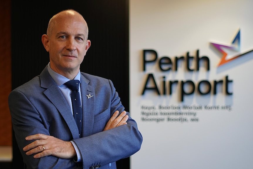 Perth Airport chief executive Kevin Brown standing alongside an airport sign.