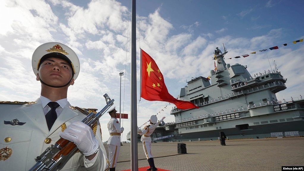中国航母山东号停泊在海南省的一个海军基地，士兵在举行升旗仪式。（资料照：2019年12月17日）