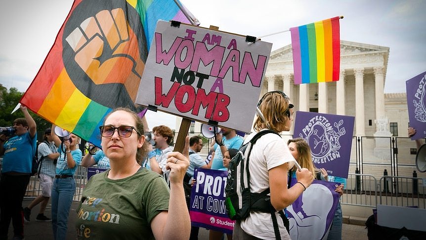 A woman holds a sign reading 