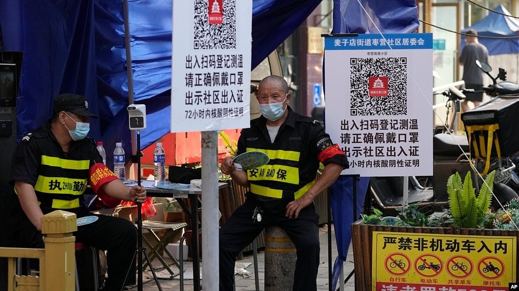 北京街头两名保安把守需要扫健康码和社区出入证方能出入的社区入口。（2022年6月20日）