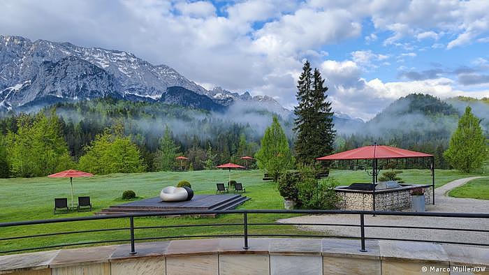 Blick von einer Terrasse von Schloss Elmau auf Wiese und Berge bei Morgennebel