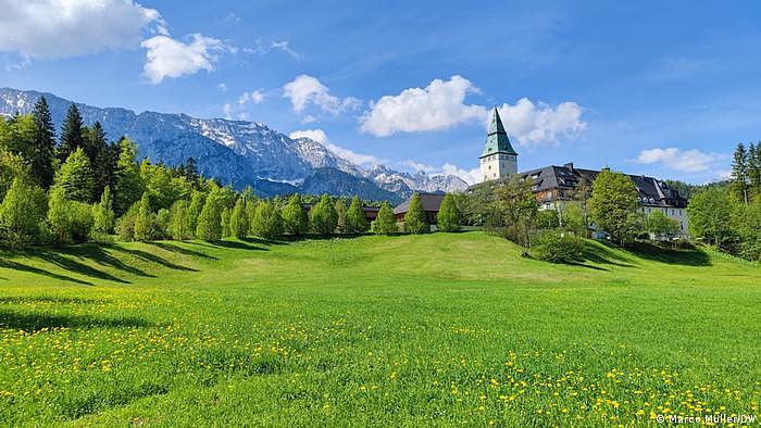 Blick auf Schloss Elmau über eine Blumenwiese