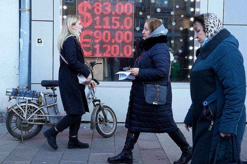 人们走过一个橱窗，里面显示俄罗斯卢布的兑换汇率