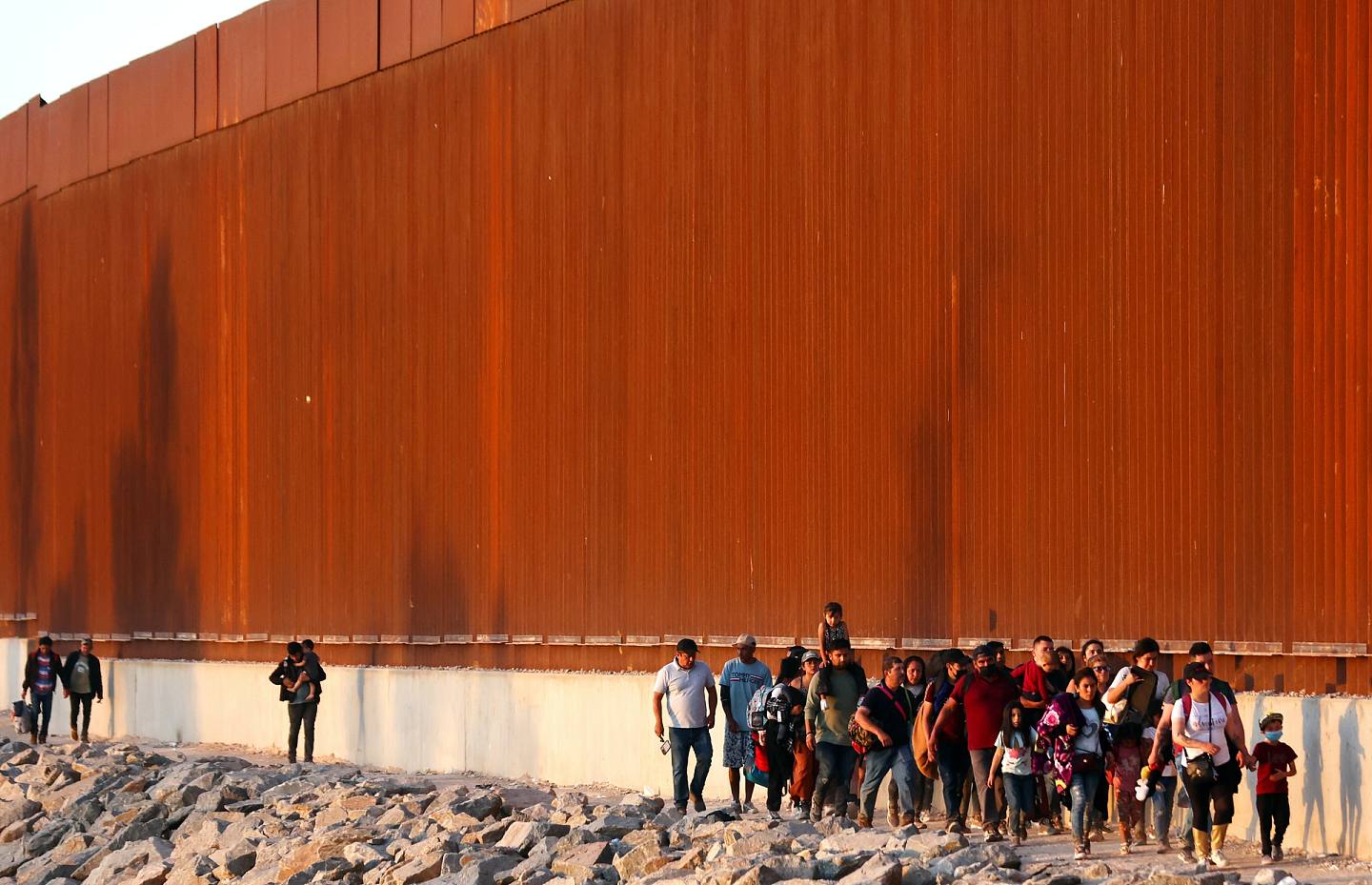 图为2021年5月，美墨边境围墙下，一些等待机会进入美国境内的人。 （AP）