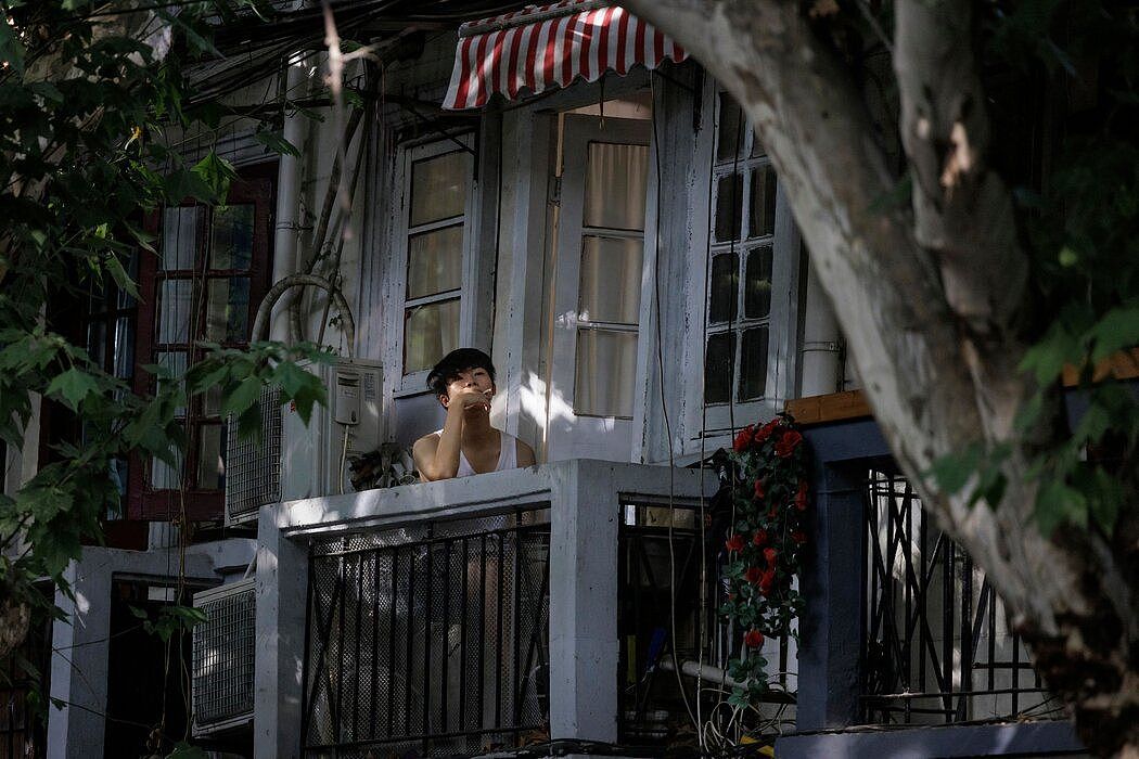 上海今年6月对一些小区采取新的限制措施后，住在封控区的一名男子坐在自家阳台上。中国遏制疫情的政策会给精神健康带来多年的不利影响。