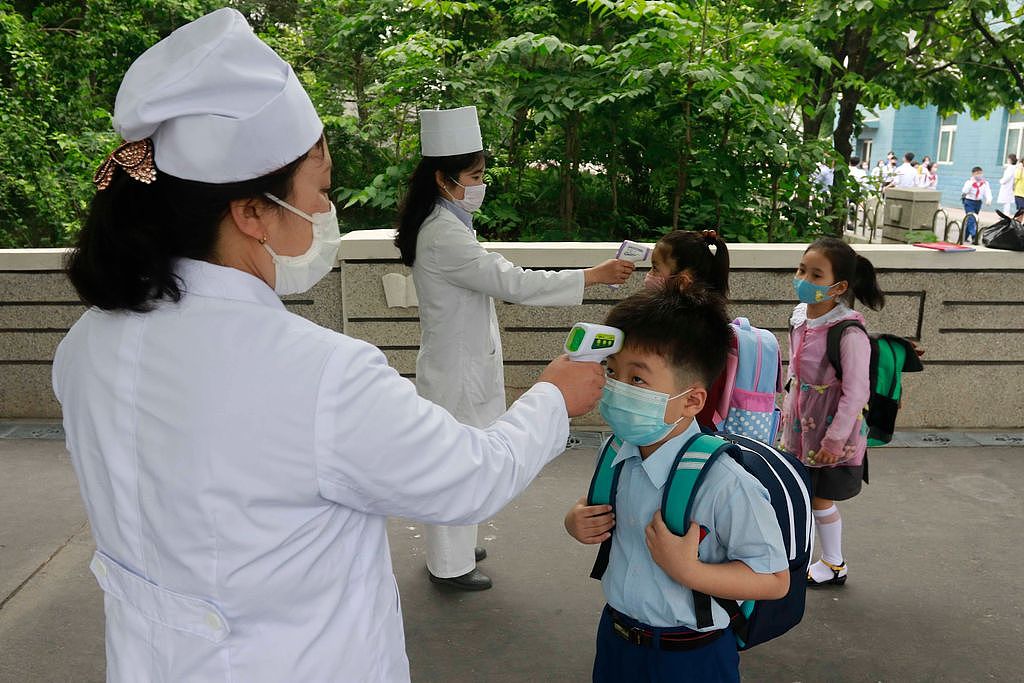 北韩一间小学校务人员6月3日在校门口为学生测量体温，以控制疫情扩散。 美联社
