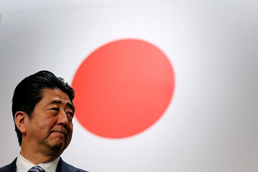 A man standing in the front of the Japanese national flag