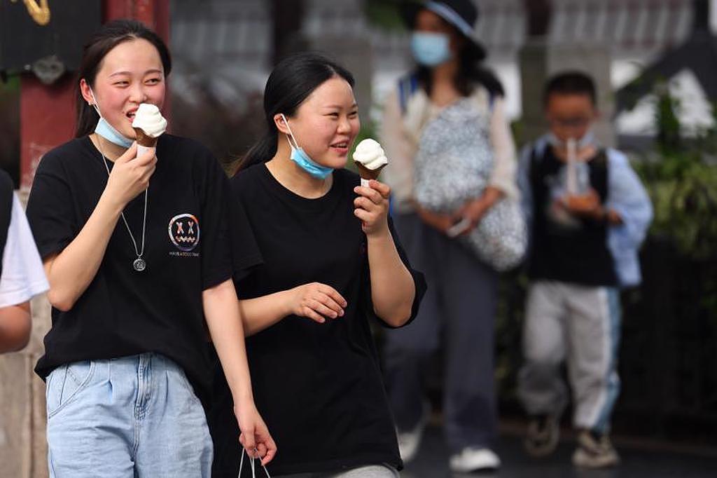 大陆全面高温，知名火炉南京高温达40℃，民众在大太阳下吃冰淇淋消暑气。 （图／中新社）