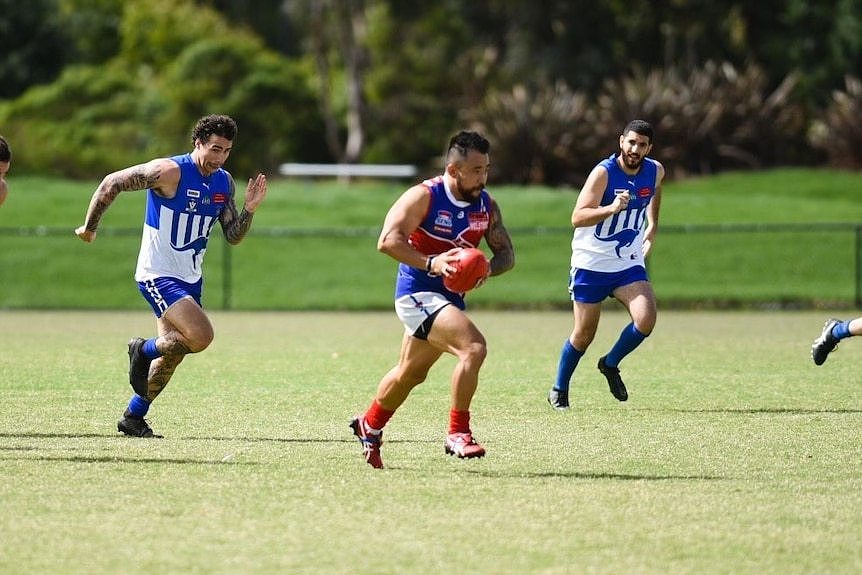 An Asian man playing Aussie rules.