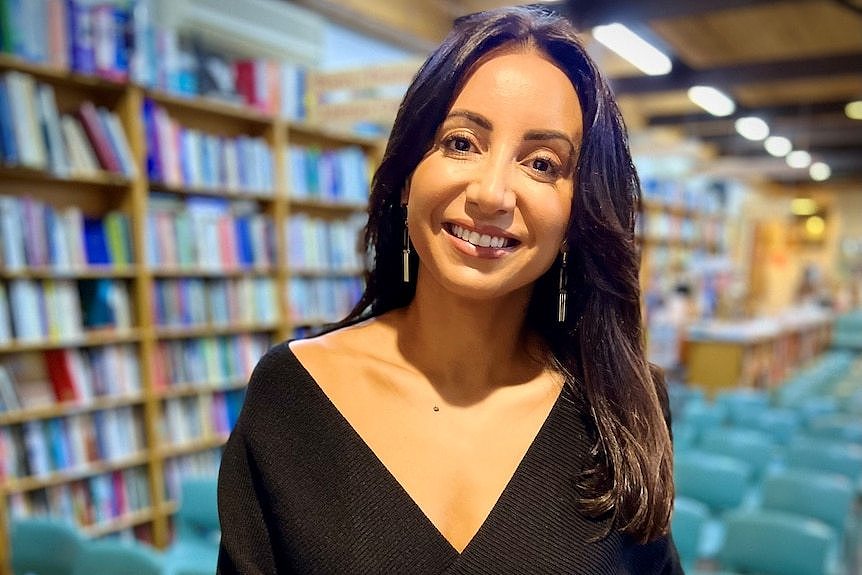 A women smiling and looking at the camera in a library.