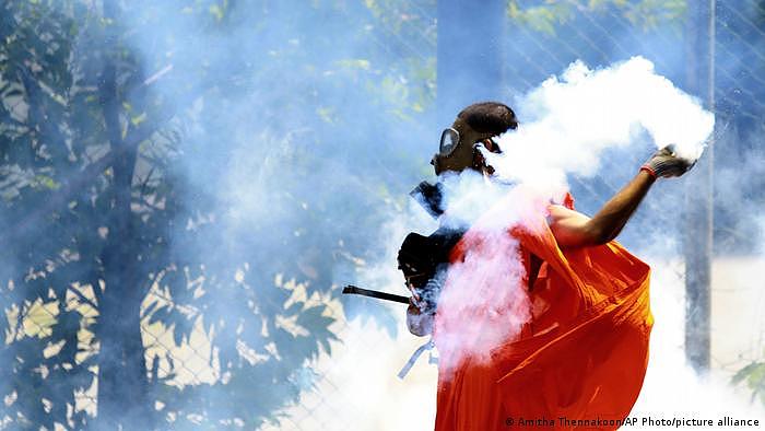 一名男子在斯里兰卡科伦坡被警察开火驱散抗议者后扔回了一个催泪瓦斯罐，