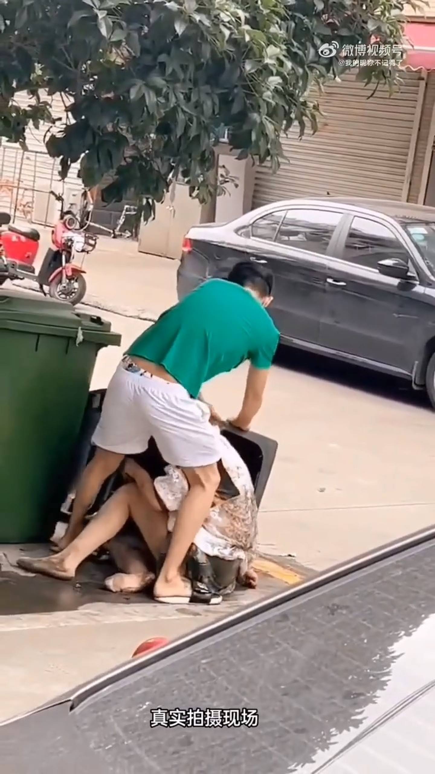 绿色男子抓着女子头发，试图强行把她塞进旁边的垃圾桶，女子不断挣扎反抗。 （影片截图）