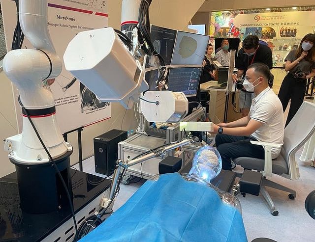 一名工作人员在香港科学园展览中演示由中国科学院香港科技创新研究院人工智能与机器人中心开发的颅内微创手术机器人系统。